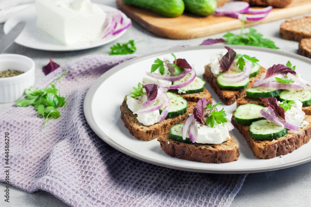 Canapes with toasted bread with sunflower and flax seeds, feta cheese, cucumber and onion