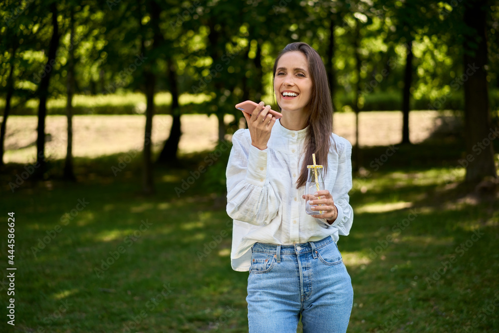 Woman talking on the phone in the park during sunny summer day