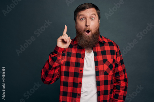 Attractive charming hipster male coworker suggest his solution method, raise index finger in eureka, lightbulb gesture, folding lips saying his plan, introduce own concept during office meeting