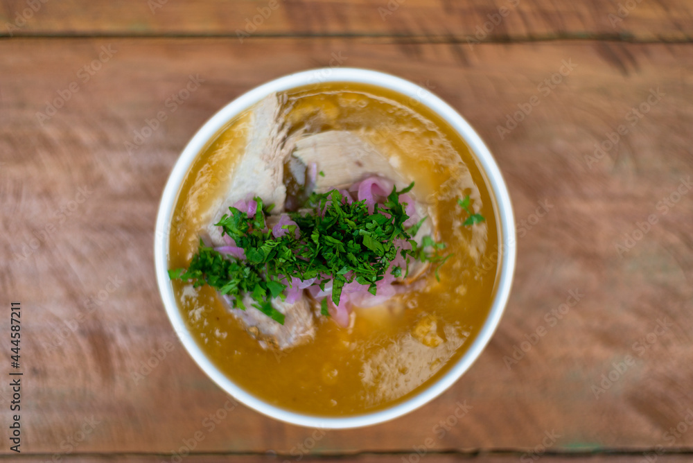 plate of traditional fish soup from the Ecuadorian coast, zenithal view, encebollado, on a wooden table. plate of traditional fish soup from the Ecuadorian coast, zenithal view, encebollado, on a wooden table.