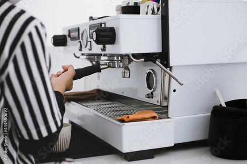 Barista using coffee machine to make coffee in cafe