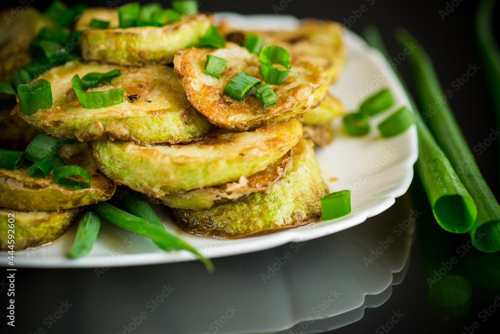 fried zucchini in circles with fresh herbs in a plate on a black fried zucchini in circles with fresh herbs in a plate on a black