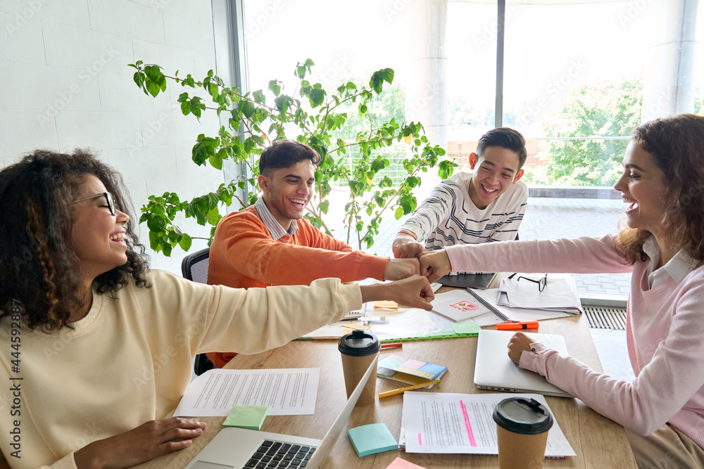© insta_photos - Young happy laughing creative startup team four multiethnic coworkers diverse students work together give fist bump celebrate successful project in office classroom at desk. Teamwork success concept. © insta_photos - Young happy laughing creative startup team four multiethnic coworkers diverse students work together give fist bump celebrate successful project in office classroom at desk. Teamwork success concept.