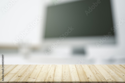 Empty wooden office table with light sunny workplace with computer on background, mock up © Pixels Hunter