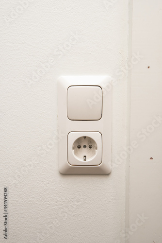 An electrical outlet and light switch on a wall.