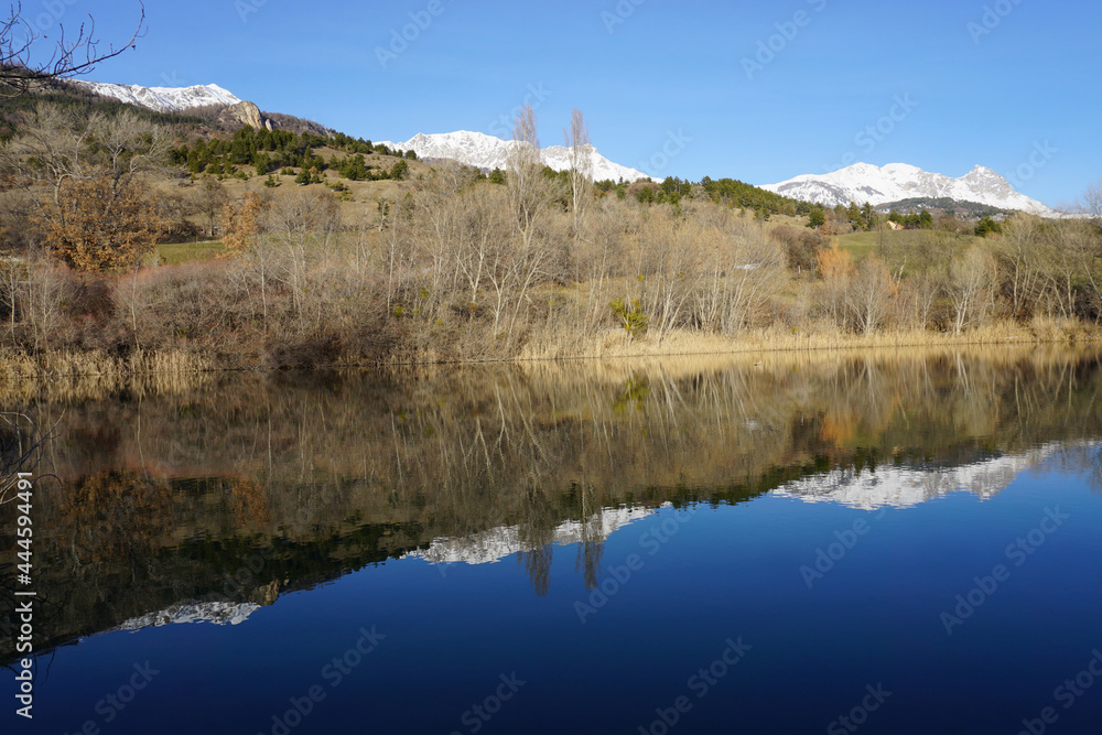 mirror reflection of the mountains with snowy peaks in the water on a clear winter day in the alps, france