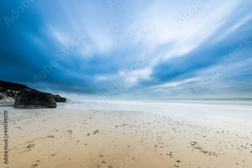 Long exposure photo of clouds rolling over a sand beach.