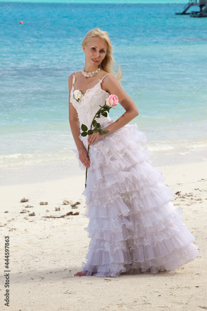 young beautiful woman in a dress of the bride at edge of the sea with a rose in a hand.. young beautiful woman in a dress of the bride at edge of the sea with a rose in a hand..