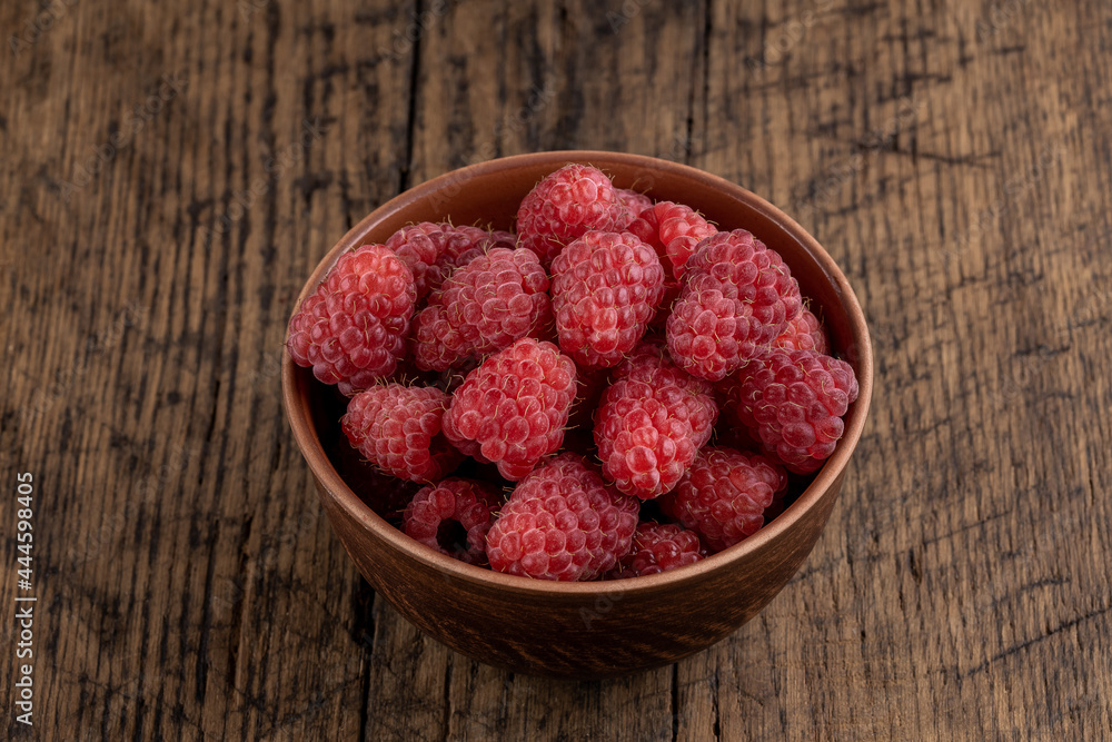 red fresh domestic raspberry at bowl on a rustic table top. space red fresh domestic raspberry at bowl on a rustic table top. space