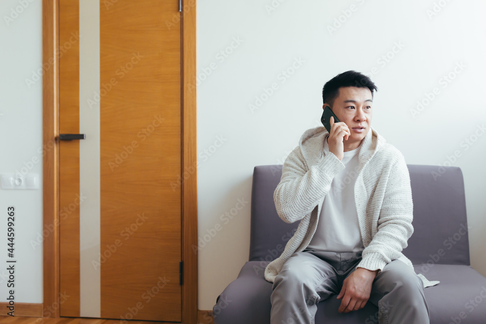 A young man is waiting in the hallway of a clinic or office center, talking on the phone and sharing news and the result of the interview, serious in everyday clothes A young man is waiting in the hallway of a clinic or office center, talking on the phone and sharing news and the result of the interview, serious in everyday clothes