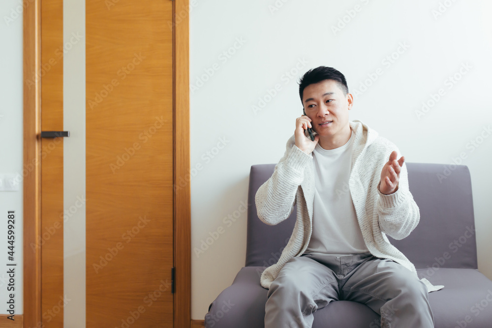 A young man is waiting in the hallway of a clinic or office center, talking on the phone and sharing news and the result of the interview, serious in everyday clothes A young man is waiting in the hallway of a clinic or office center, talking on the phone and sharing news and the result of the interview, serious in everyday clothes