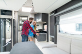 Woman and man testing interior of camper they want to buy or rent checking the kitchenette