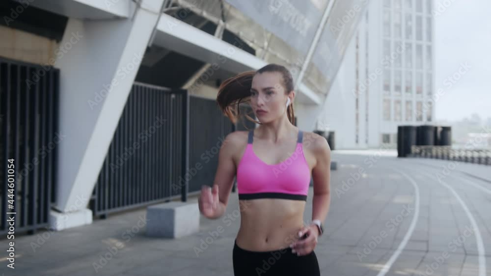 Confident young woman in sports clothing running outdoors Confident young woman in sports clothing running outdoors