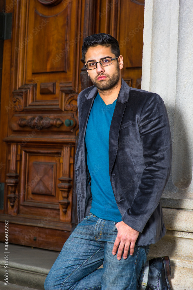 Dressing in a dark purple woolen blazer, sweater and jeans, wearing glasses, a young scholar with bread and mustache is causally standing in the doorway, seriously looking at you and listening.. Dressing in a dark purple woolen blazer, sweater and jeans, wearing glasses, a young scholar with bread and mustache is causally standing in the doorway, seriously looking at you and listening..