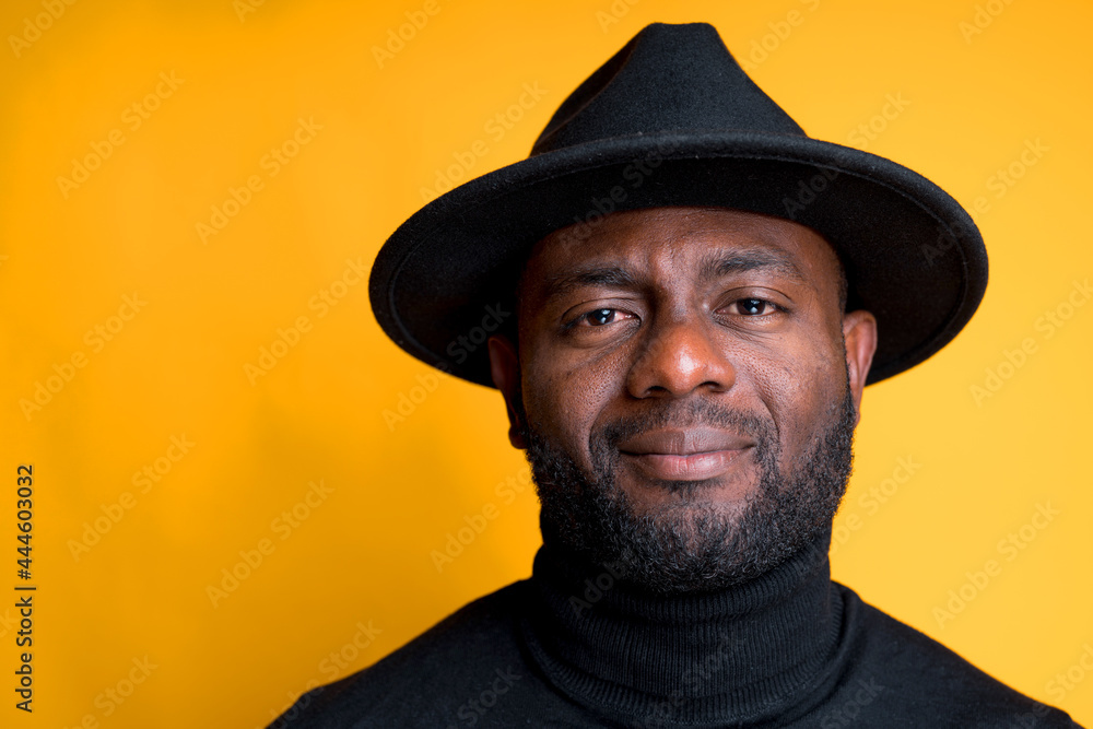 Portrait of an African American man in a black turtleneck and hat. Isolated on yellow background Portrait of an African American man in a black turtleneck and hat. Isolated on yellow background