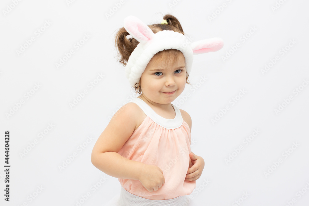 Charming girl in dress and white ears posing as cute bunny on gray background Charming girl in dress and white ears posing as cute bunny on gray background