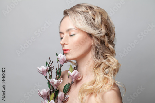 Nice woman with clean fresh skin on face and flowers. Female model with closel eyes, facial treatment. Cosmetology, beauty and spa.