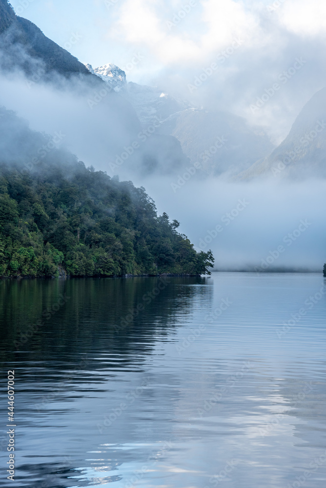 Naklejka premium A new morning dawning at Doutful Sound, clouds hanging low in the mountains, Fiordland National Park, New Zealand