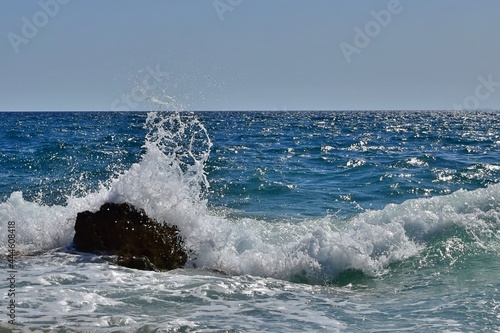 Splashing of waves crashing on stones against background of blue sea