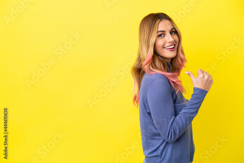 Young woman over isolated yellow background proud and self-satisfied