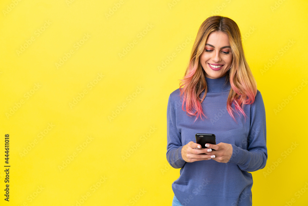 Young woman over isolated yellow background sending a message with the mobile Young woman over isolated yellow background sending a message with the mobile