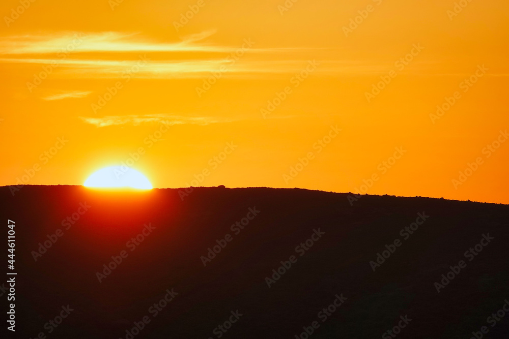 orange sunset between mountains and sun