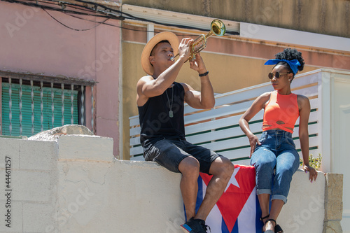 Fototapeta Naklejka Na Ścianę i Meble -  Latina woman watching a latino man playing a trumpet: Selective focus. Music and diversity concept.