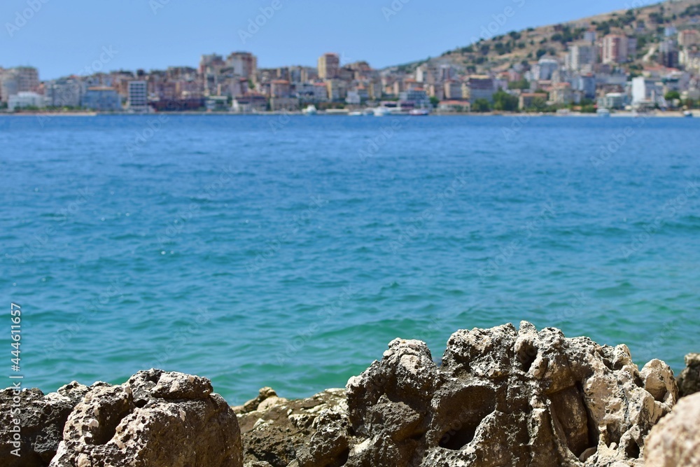 Stone coast on blurred background of sea bay and mediterranean city