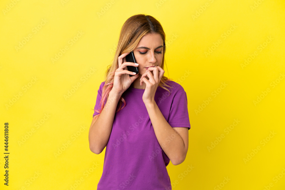 Young woman using mobile phone over isolated yellow background having doubts Young woman using mobile phone over isolated yellow background having doubts