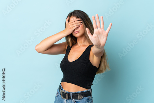 Young caucasian woman isolated on blue background making stop gesture and covering face