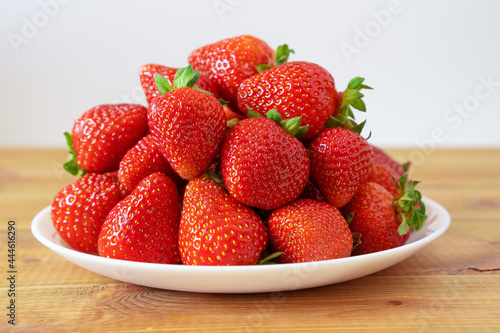 Plate of sweet ripe strawberries on wooden table. Delicious summer berries.