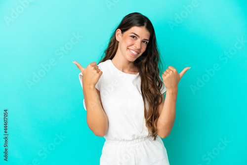 Young caucasian woman isolated on blue background with thumbs up gesture and smiling