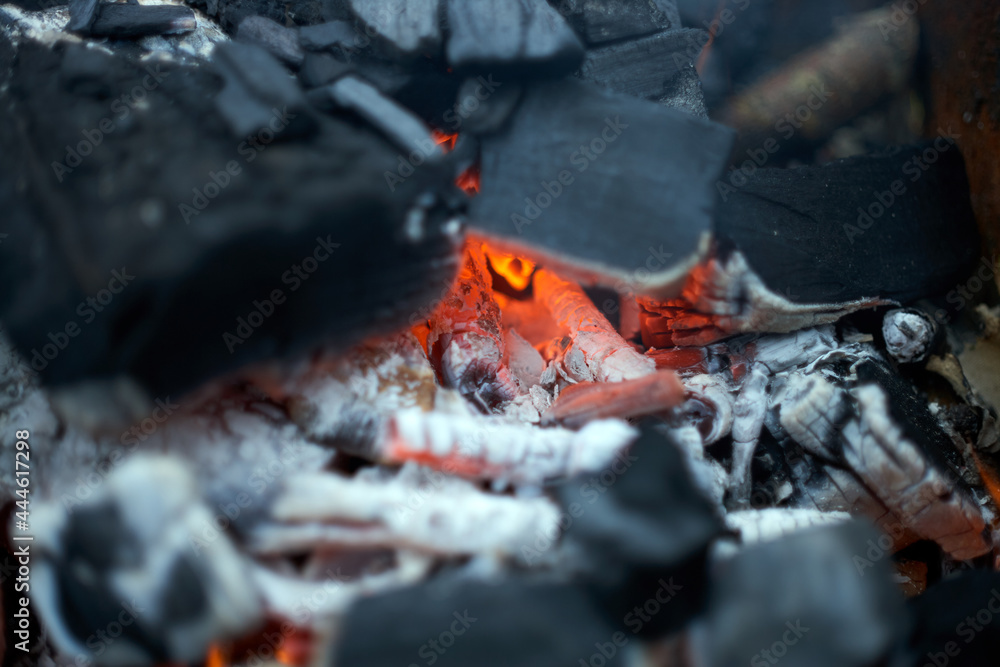 Hot charcoal glowing and flaming In fireplace with flames background texture, close-up. 