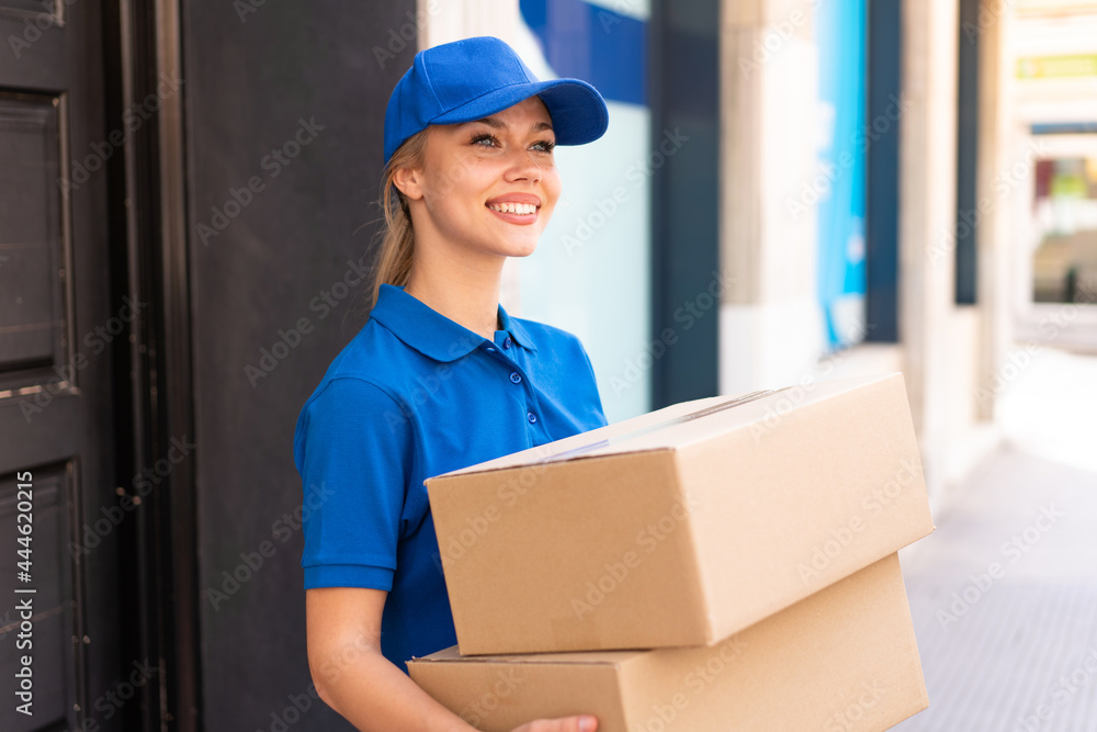 Young delivery woman at outdoors holding boxes with happy expression Young delivery woman at outdoors holding boxes with happy expression