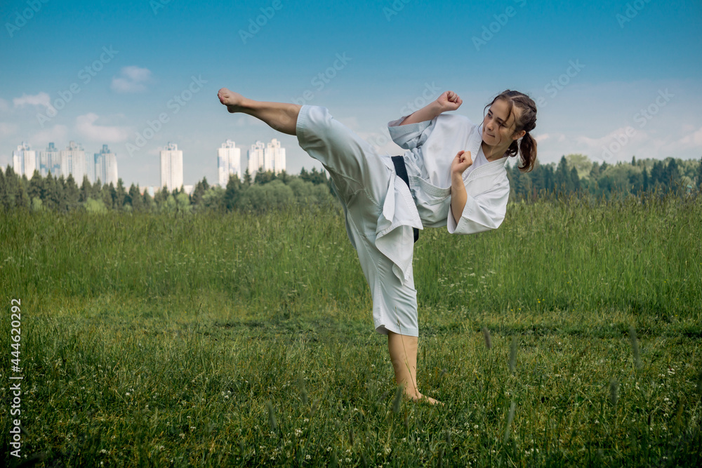 teenage girl training karate kata outdoors, performs the uro mawashi geri (hook kick) teenage girl training karate kata outdoors, performs the uro mawashi geri (hook kick)