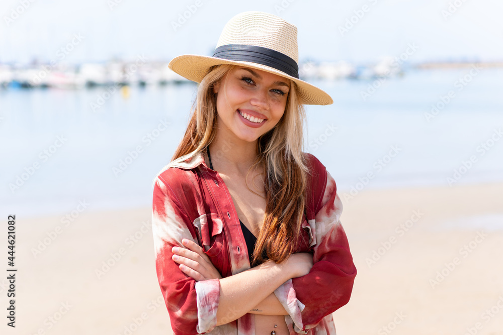 Young pretty woman in summer holidays at beach keeping the arms crossed in frontal position