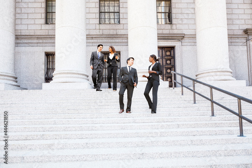 Fototapeta Four well dressed professionals walk down steps in discussion outside of a courthouse or municipal building