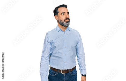 Middle aged man with beard wearing business shirt smiling looking to the side and staring away thinking.