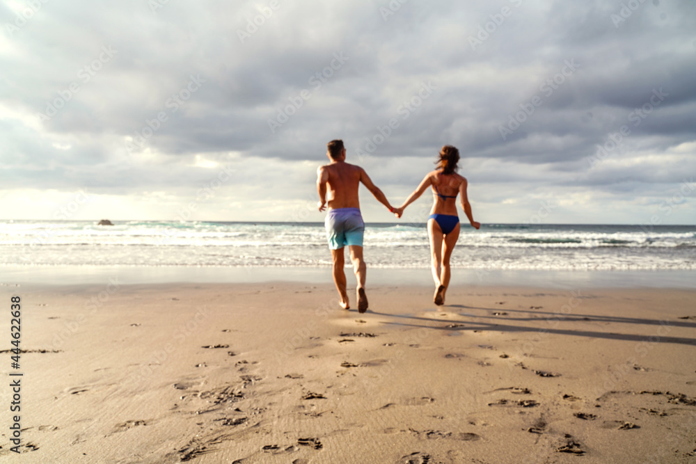 Happy Couple running on the beach, having fun on romantic honeymoon vacation