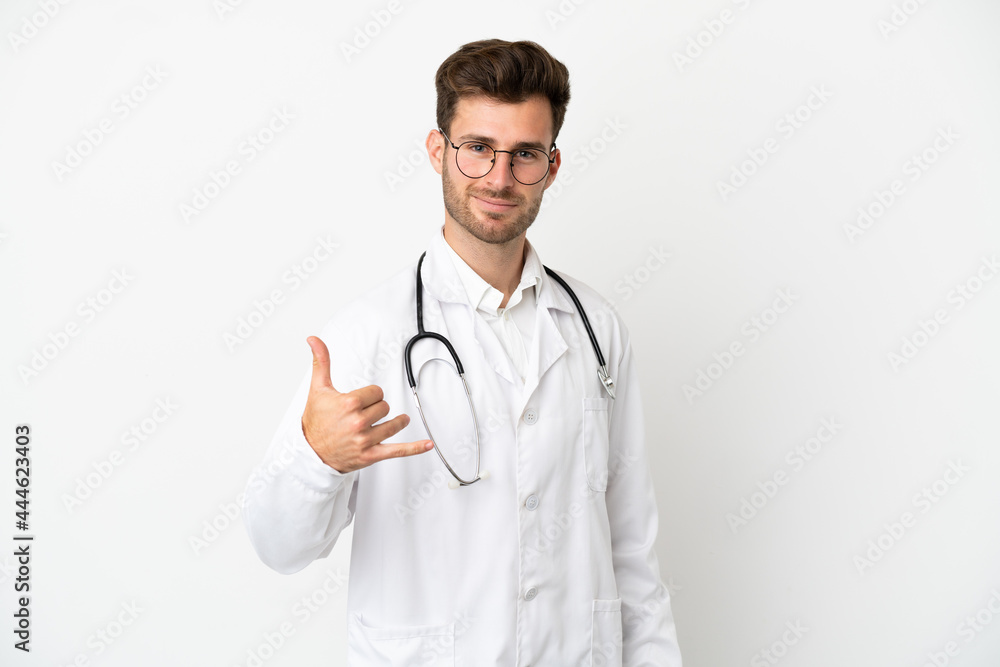 Young doctor caucasian man over isolated on white background wearing a doctor gown and making phone gesture Young doctor caucasian man over isolated on white background wearing a doctor gown and making phone gesture