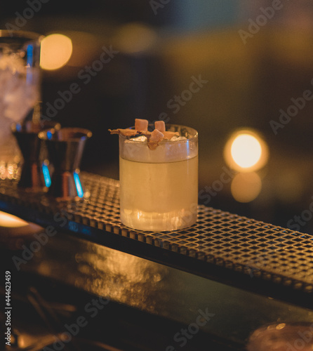 Vertical shot of penicillin cocktail glass on the bar stand isolated on blurry background photo