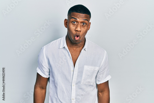 Young black man wearing casual white shirt afraid and shocked with surprise expression, fear and excited face.