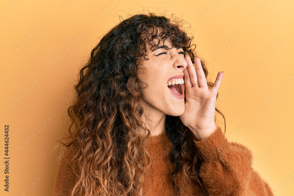 Young hispanic girl wearing casual clothes shouting and screaming loud to side with hand on mouth. communication concept. Young hispanic girl wearing casual clothes shouting and screaming loud to side with hand on mouth. communication concept.
