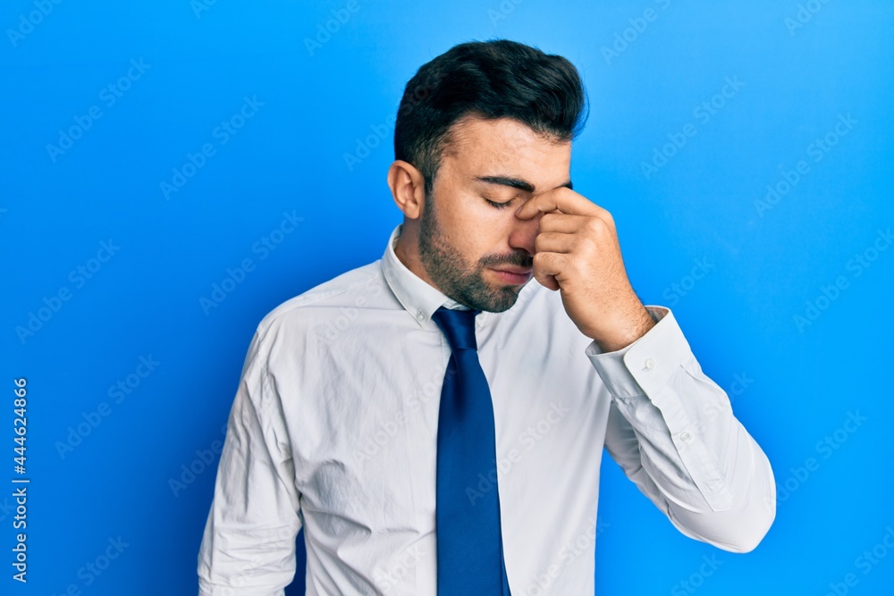 Young hispanic man wearing business clothes tired rubbing nose and eyes feeling fatigue and headache. stress and frustration concept. Young hispanic man wearing business clothes tired rubbing nose and eyes feeling fatigue and headache. stress and frustration concept.