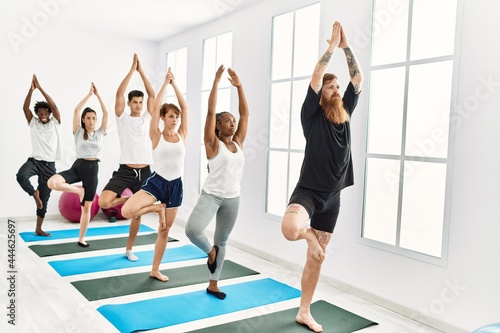 Group of young people concentrate training yoga at sport center.