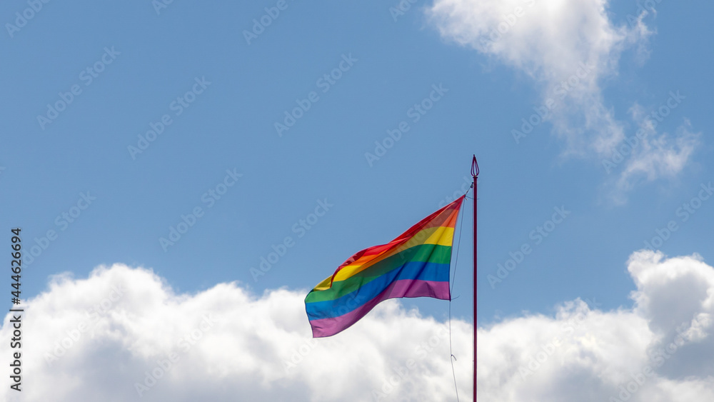 Worldwide LGBTQ community concept with rainbow flag waving in the air with blue sky and white clouds as background, Celebration of Pride month, The symbol of lesbian, gay, bisexual and transgender.