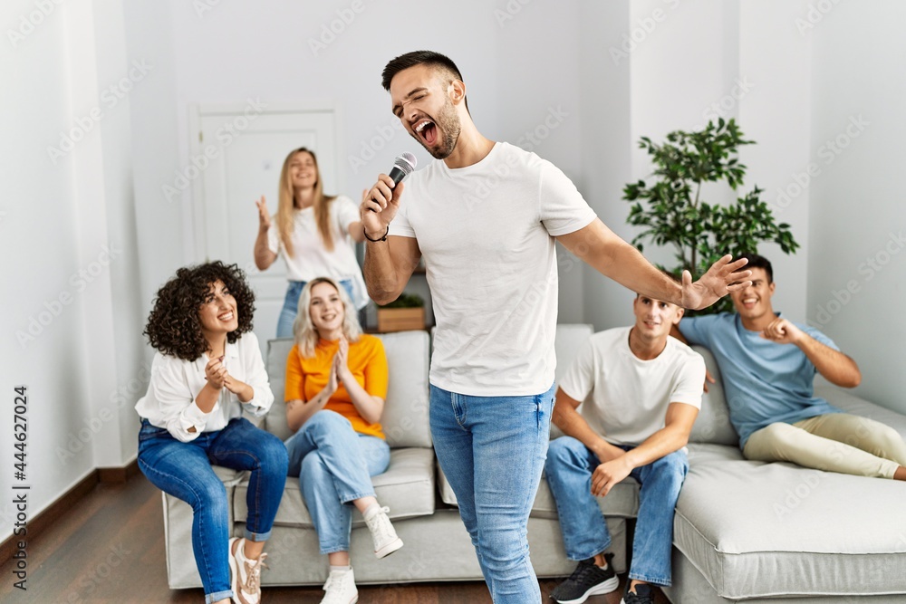 Group of young friends having party singing song using microphone at home. Group of young friends having party singing song using microphone at home.