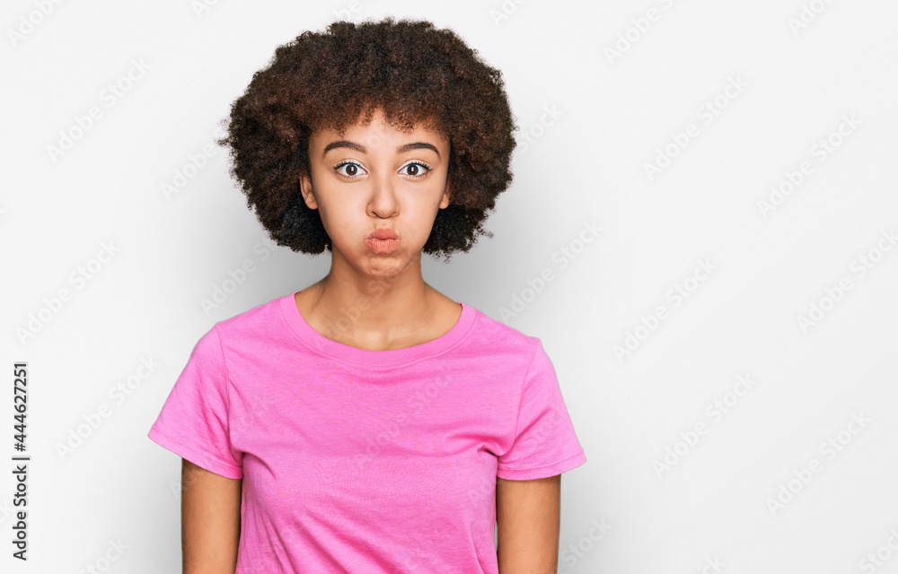 Young hispanic girl wearing casual clothes puffing cheeks with funny face. mouth inflated with air, crazy expression. Young hispanic girl wearing casual clothes puffing cheeks with funny face. mouth inflated with air, crazy expression.