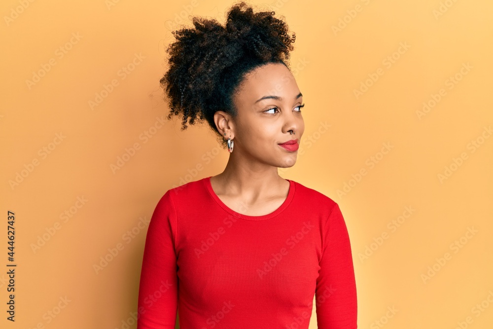 Young african american girl wearing casual clothes looking to side, relax profile pose with natural face and confident smile. Young african american girl wearing casual clothes looking to side, relax profile pose with natural face and confident smile.