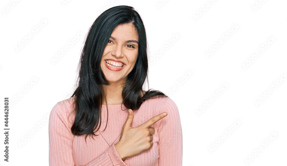 Young hispanic woman wearing casual clothes cheerful with a smile of face pointing with hand and finger up to the side with happy and natural expression on face Young hispanic woman wearing casual clothes cheerful with a smile of face pointing with hand and finger up to the side with happy and natural expression on face